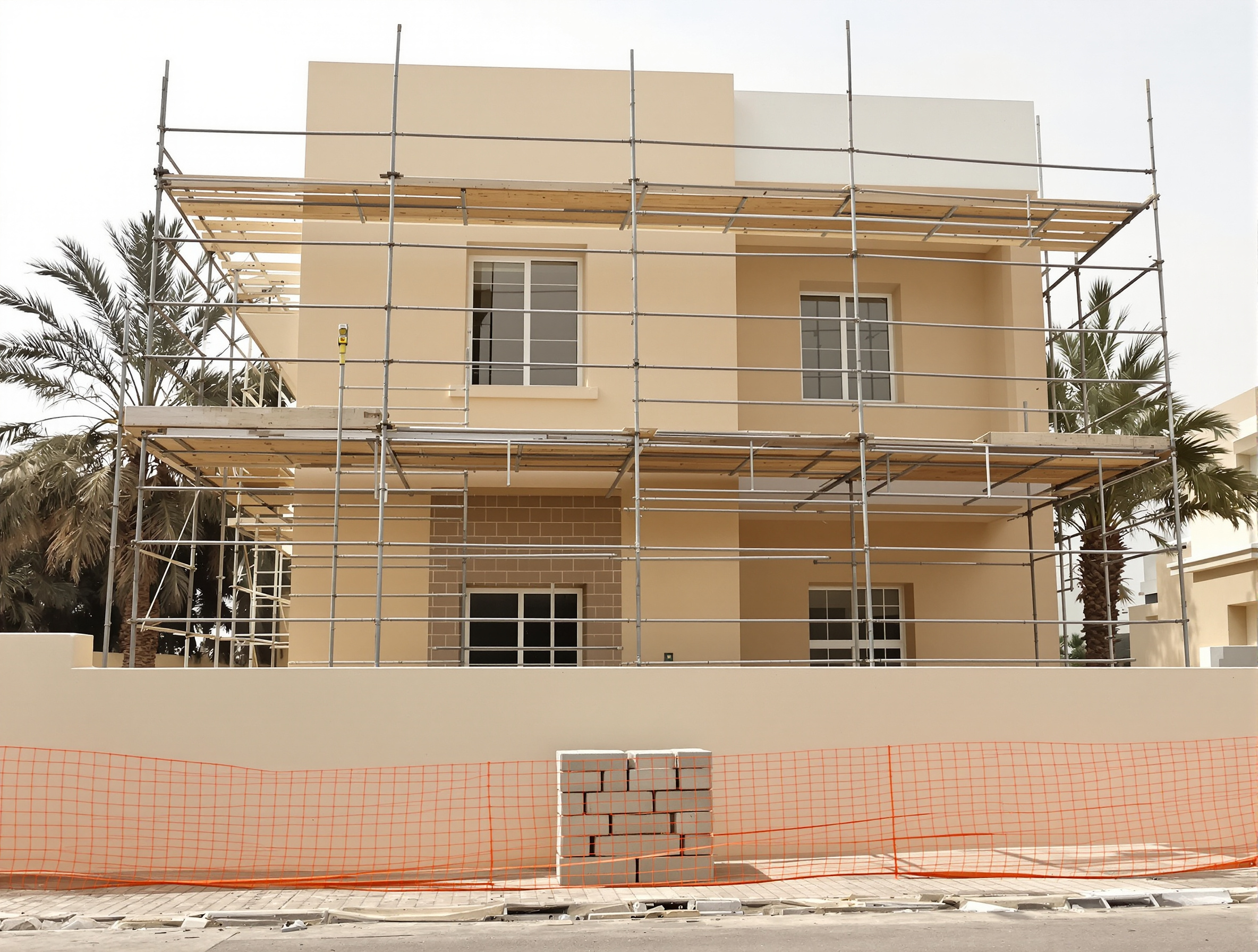 The street facade of a two-storey Dubai villa under renovation, fresh render still drying